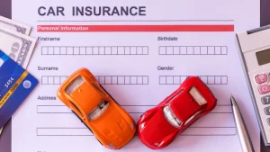 Car insurance form with toy cars, money, and credit cards