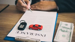 Insurance agent reviewing car insurance form with money and keys