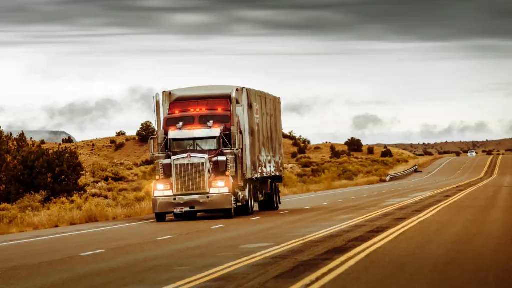 Large truck driving on a highway with a scenic landscape in the background.